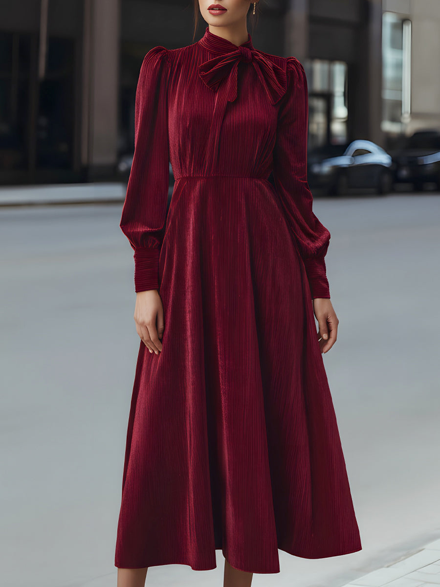 Burgundy velvet pleated bow-neck midi dress by Christine Brewer, elegant cocktail dress with a fitted waist and flowing skirt.