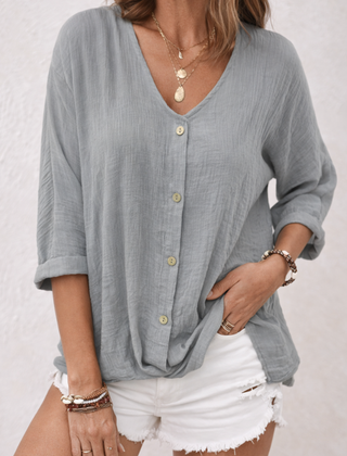 Grey women's V-neck button-front blouse from Christine Brewer's Aria collection, shown on a hanger.
