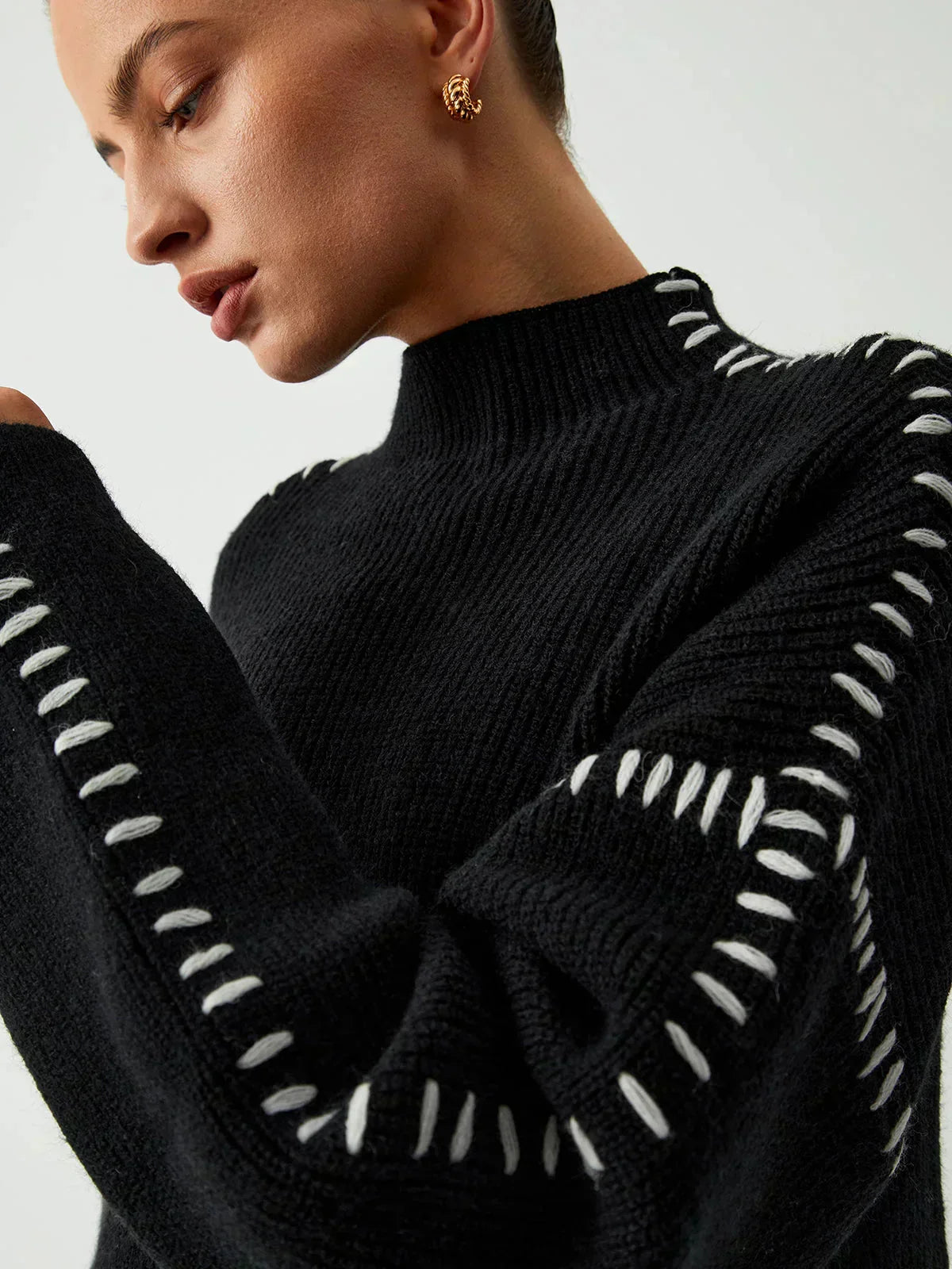 Black ribbed wool mock neck oversized sweater with whipstitch details, designed for autumn wear by Christine Brewer.
