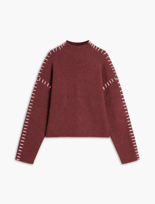 Red ribbed wool mock neck sweater by Christine Brewer featuring whipstitch details, oversized and tailored for autumn wear.