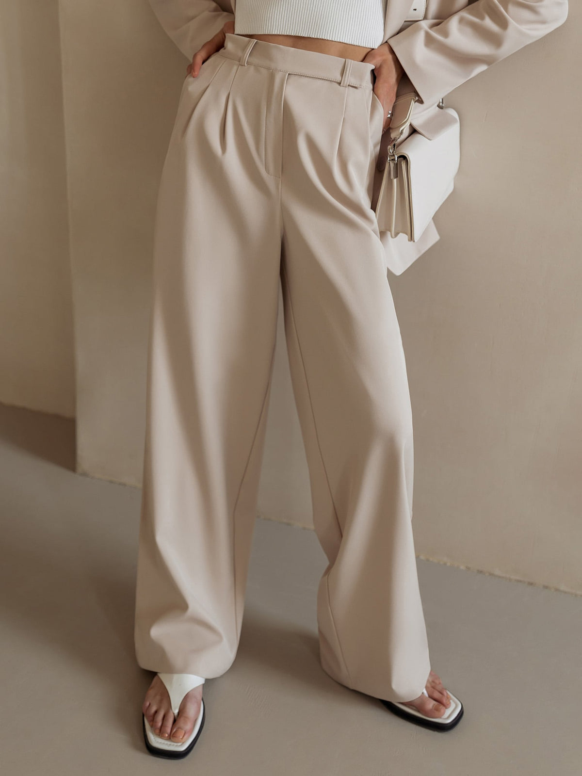 White wide-leg high-waist women's trousers by Christine Brewer, shown on a model, featuring a relaxed fit and tailored design.