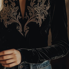 Black velvet V-neck long sleeve top with embroidered details by Christine Brewer, shown on a white background.