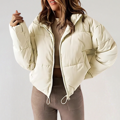Beige Emma high collar puffer jacket for women by Christine Brewer, showcasing the stylish, insulated design and high collar detail.