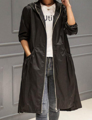 Women’s Scarlett waterproof longline trench coat with hood, stylish and rainproof, by Christine Brewer, shown on a model outdoors.