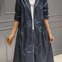 Woman wearing a black hooded waterproof longline trench coat by Christine Brewer, featuring a hood and sleek waterproof design.