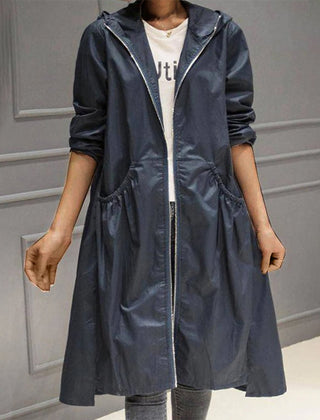 Woman wearing a black hooded waterproof longline trench coat by Christine Brewer, featuring a hood and sleek waterproof design.