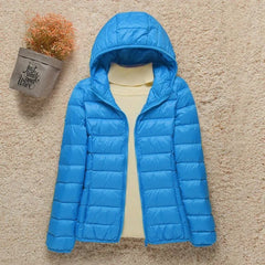 Women's lightweight hooded quilted puffer jacket by Christine Brewer, shown in a packable, stylish design with a hood and quilting.