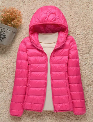 Women's lightweight hooded quilted jacket by Christine Brewer, packable puffer style, shown in a casual outdoor setting.