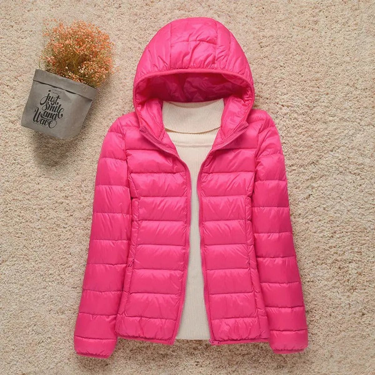 Women's lightweight hooded quilted jacket by Christine Brewer, packable puffer style, shown in a casual outdoor setting.
