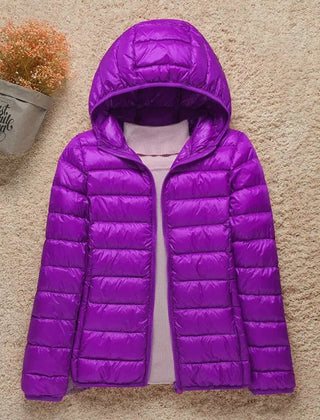 Woman wearing Christine Brewer Eleanor lightweight hooded quilted puffer jacket, showcasing its packable, insulated design.