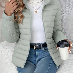 Women's lightweight quilted puffer coat with stand collar and zip-up front by Christine Brewer, shown in a stylish outdoor setting.