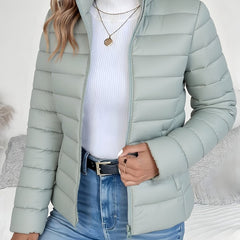 Women's lightweight quilted puffer coat with stand collar and zip-up front by Christine Brewer, shown in a stylish outdoor setting.