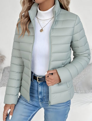 Women's lightweight quilted puffer coat with stand collar and zip-up front by Christine Brewer, shown in a stylish outdoor setting.