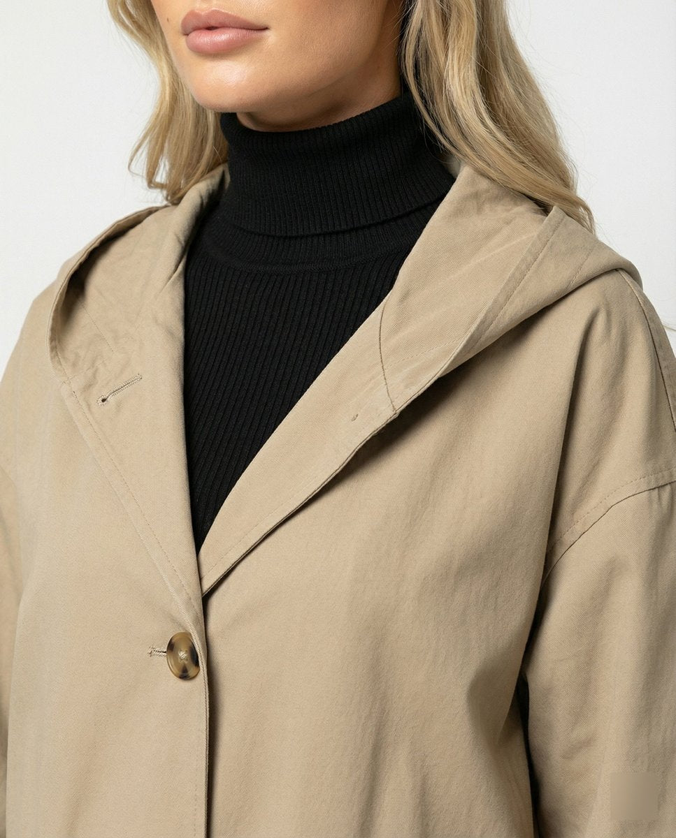 Rosie women's long waterproof windproof hooded trench coat by Christine Brewer, shown in beige with a belt and large front pockets.