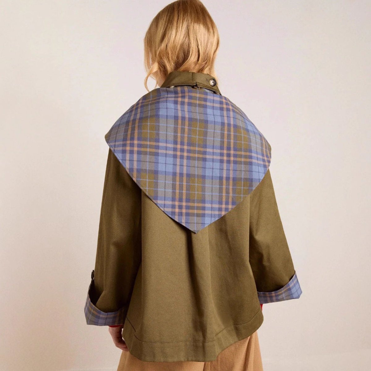 Women's oversized double-breasted trench coat with tartan lining and collar by Christine Brewer, shown on a model.