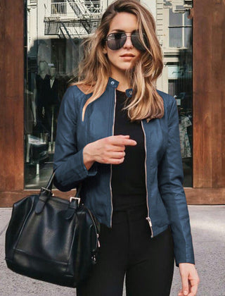 Women’s slim-fit zip-up faux leather jacket by Christine Brewer, shown in a close-up of the black jacket with silver zipper details.